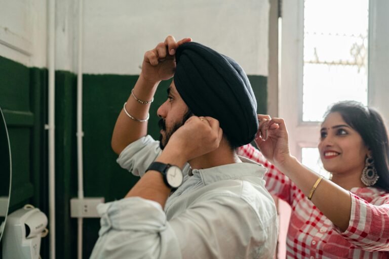 A Sikh couple lovingly adjusts a turban at home, reflecting culture and morning routine.