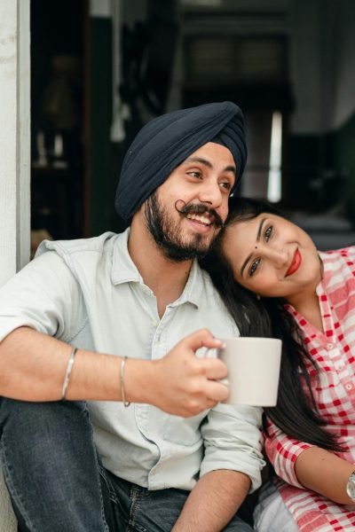 Happy Indian couple relaxing at home with coffee, embracing love and leisure.